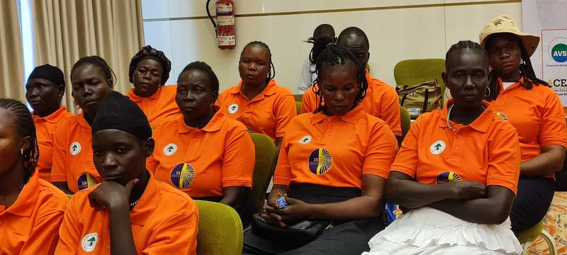 Women participants in orange shirts listening during a session